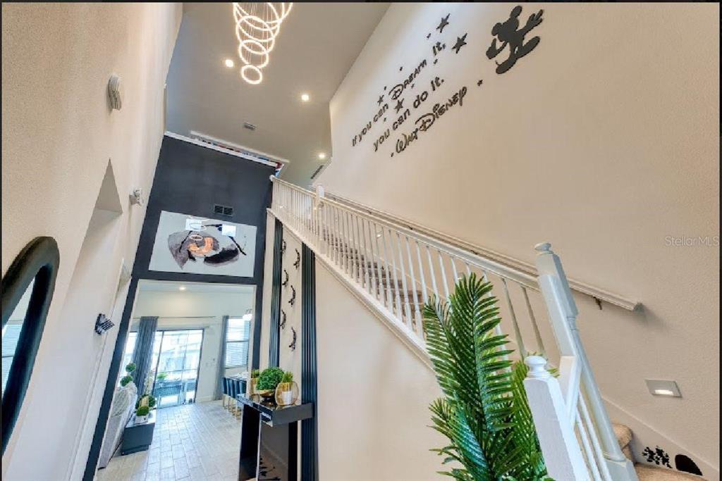 A high-ceilinged entryway features a staircase with white railings and a Walt Disney wall decal — 6301 SAND SKIPPER ROAD, ORLANDO, FL
