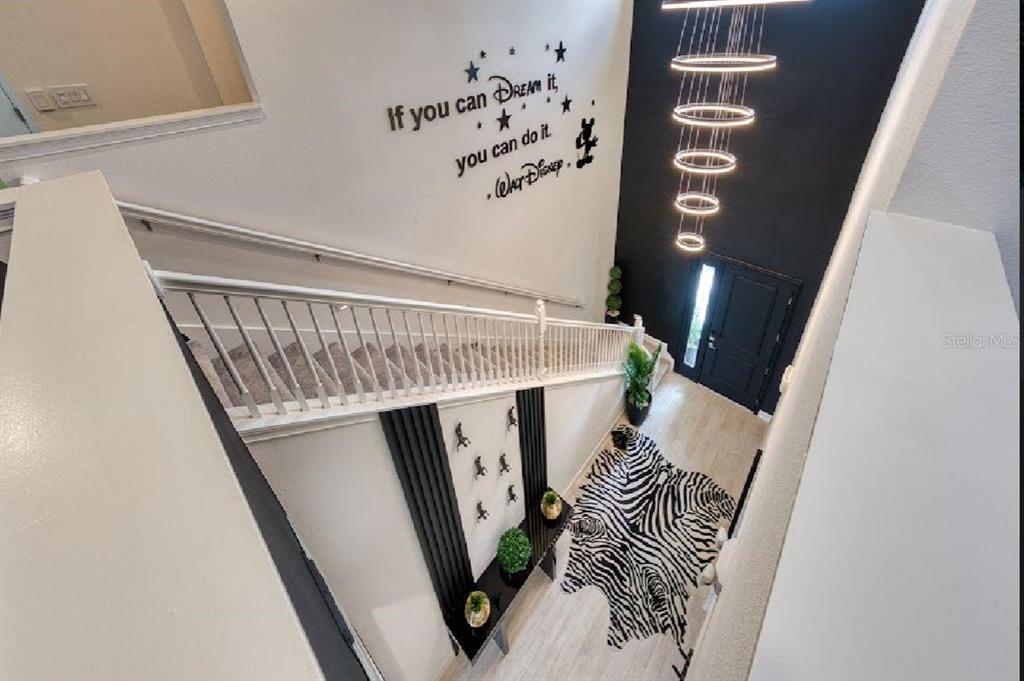 A high-angle view of a foyer with a staircase, a zebra-print rug, and wall decals — 6301 SAND SKIPPER ROAD, ORLANDO, FL