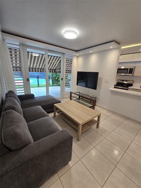 A dining area with a glass-top table and wooden chairs opens into a modern kitchen — 109 CALLE PLUMOSO REAL UNIT H104, GUAYNABO, PR