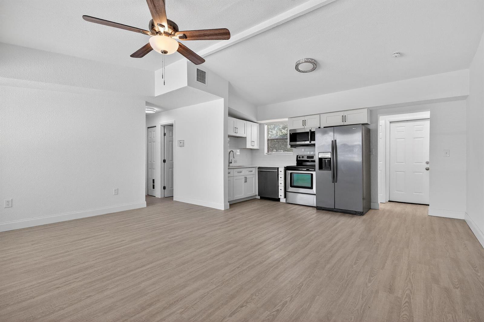 An open-concept living area features light wood-look flooring, a ceiling fan, and a modern kitchen — 3600 SW 46th Avenue, West Park FL 33023, WEST PARK, FL