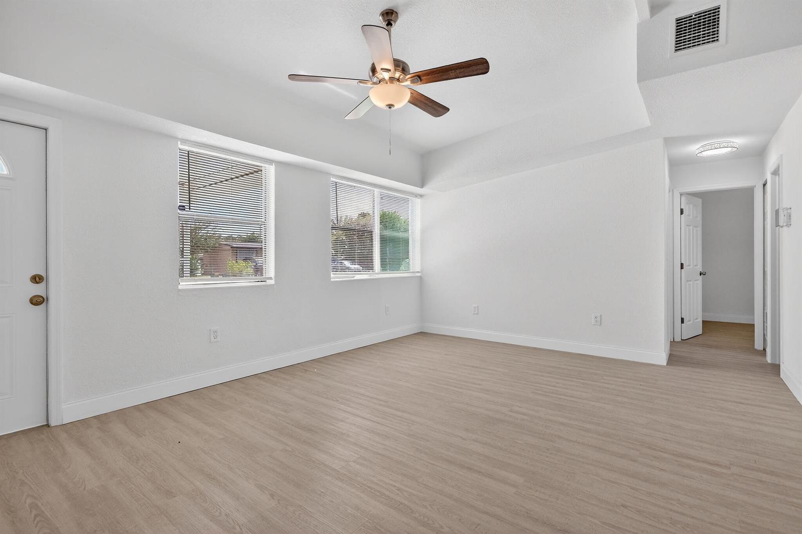 An empty room with white walls, light wood-look flooring, two windows, and a ceiling fan — 3600 SW 46th Avenue, West Park FL 33023, WEST PARK, FL