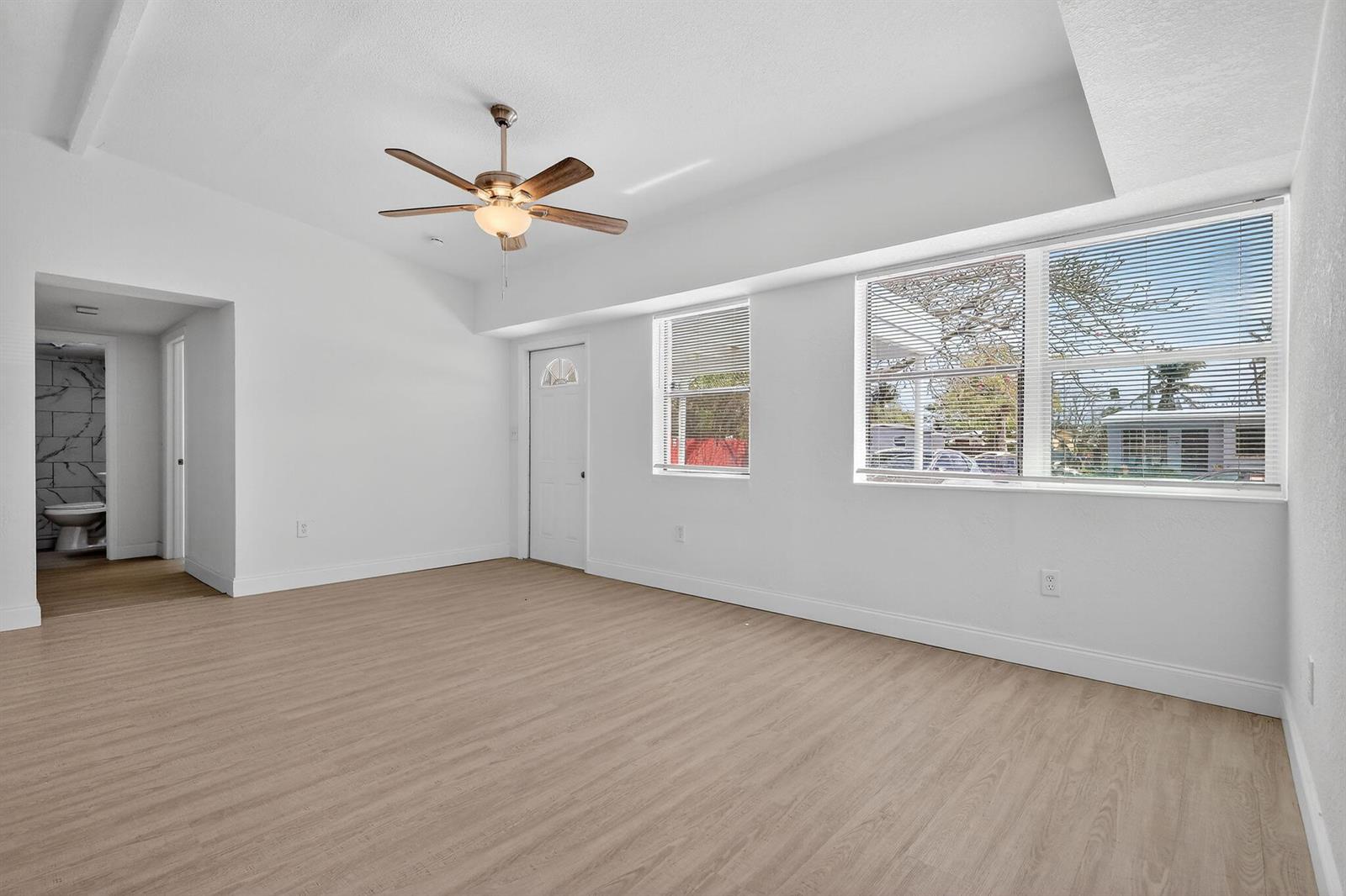 An empty room with light wood-look flooring, a ceiling fan, and large windows — 3600 SW 46th Avenue, West Park FL 33023, WEST PARK, FL