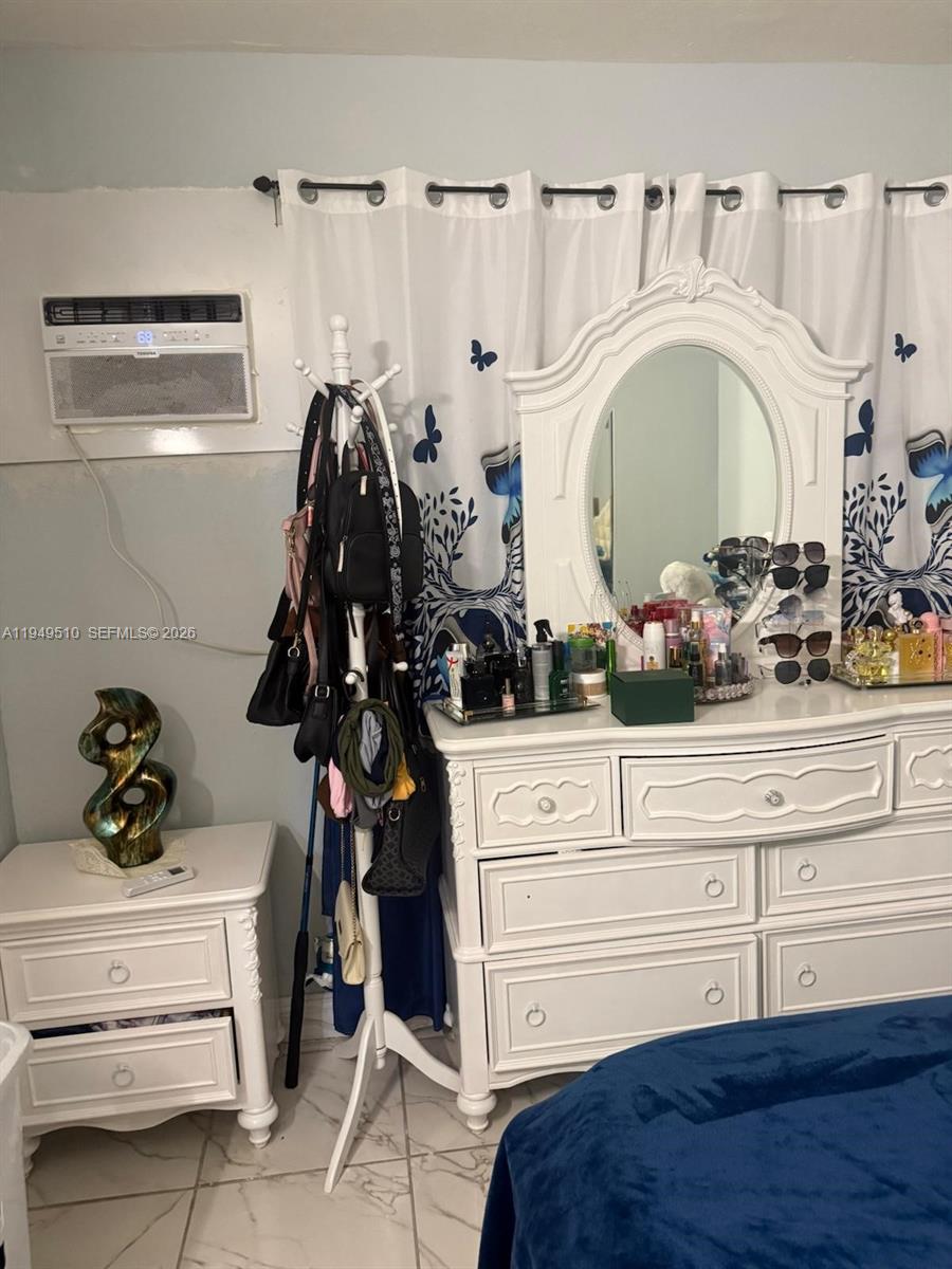 A bedroom features a white dresser with a mirror, a nightstand, and a coat rack — 350 E 21st St # 108, Hialeah FL 33010, HIALEAH, FL