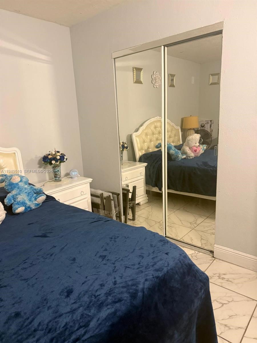 A bedroom features a bed with a blue cover, a white nightstand, and mirrored closet doors — 350 E 21st St # 108, Hialeah FL 33010, HIALEAH, FL