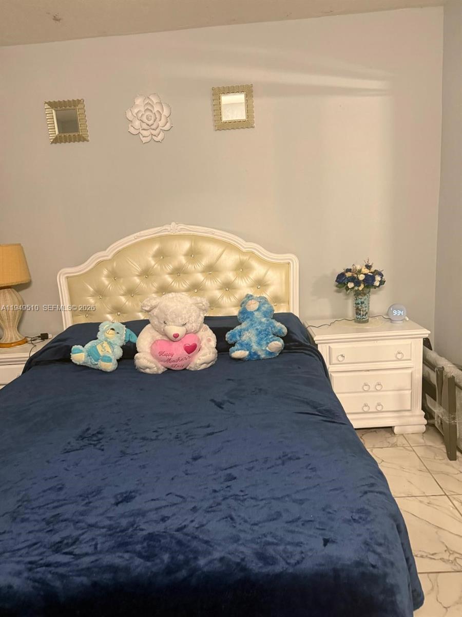 A bedroom features a tufted white headboard, a blue bedspread, and a white nightstand — 350 E 21st St # 108, Hialeah FL 33010, HIALEAH, FL
