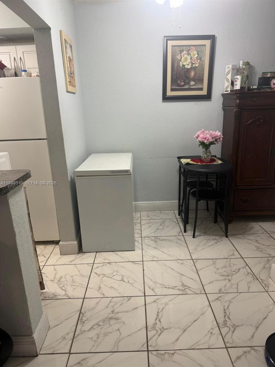 A small kitchen area features a chest freezer, a small dining table, and tiled floors — 350 E 21st St # 108, Hialeah FL 33010, HIALEAH, FL