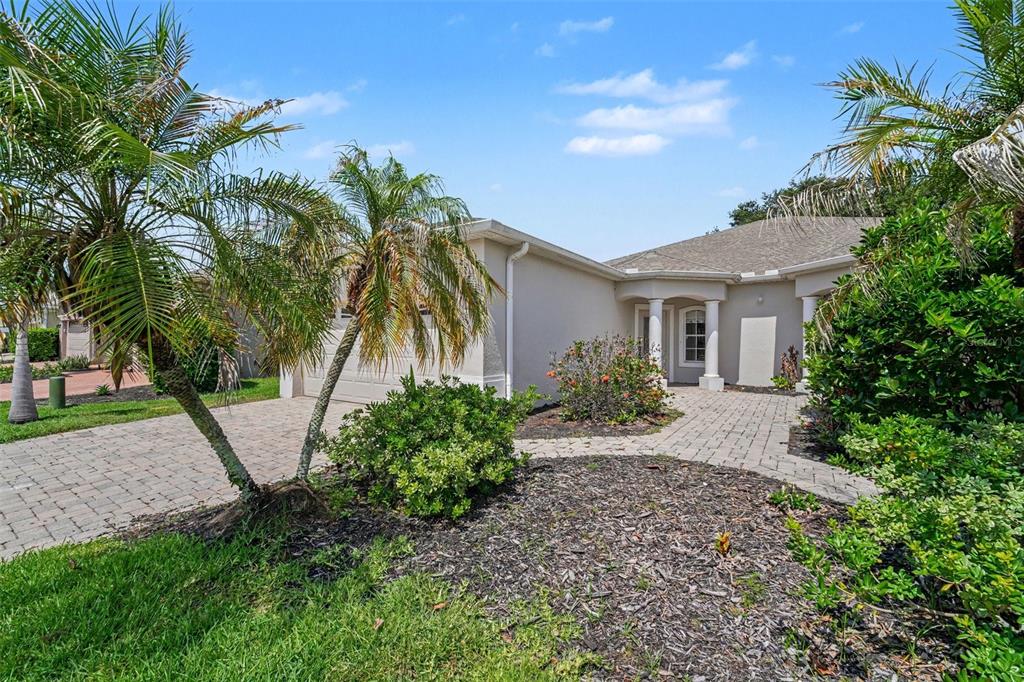 The exterior of a single-story house features a paved driveway, palm trees, and landscaping — 1819 TULLAGEE AVENUE AVENUE, MELBOURNE, FL