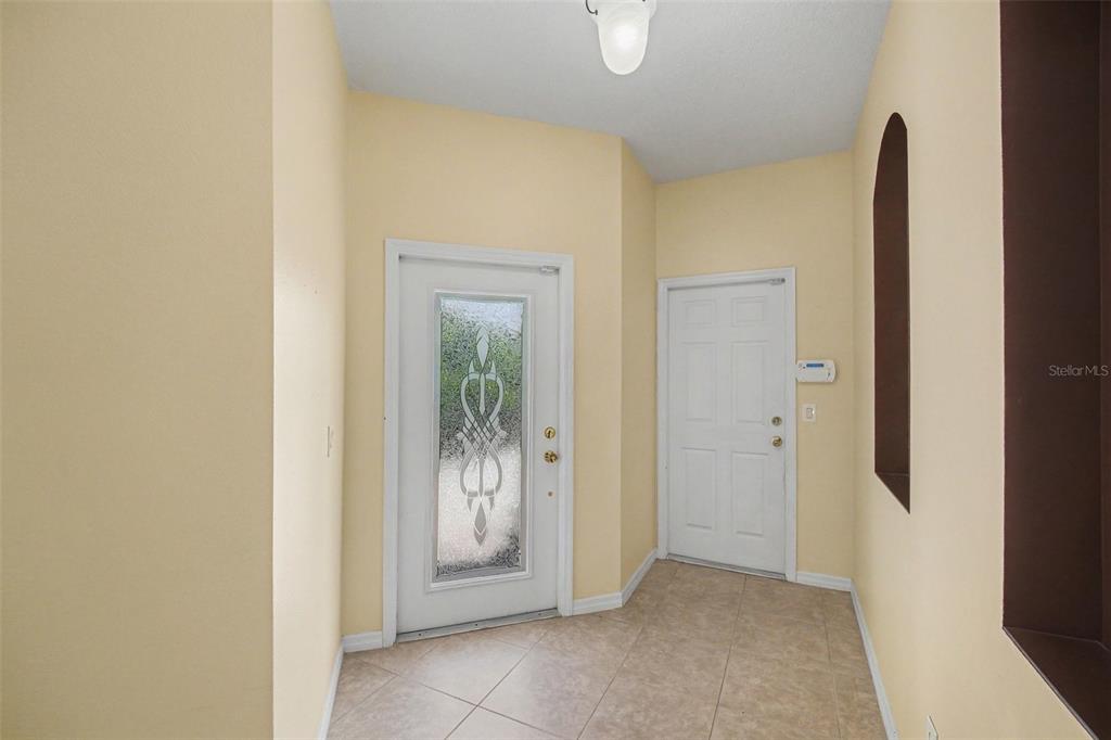 An entryway features light-colored walls, tiled flooring, a decorative front door, and a side door — 1819 TULLAGEE AVENUE AVENUE, MELBOURNE, FL