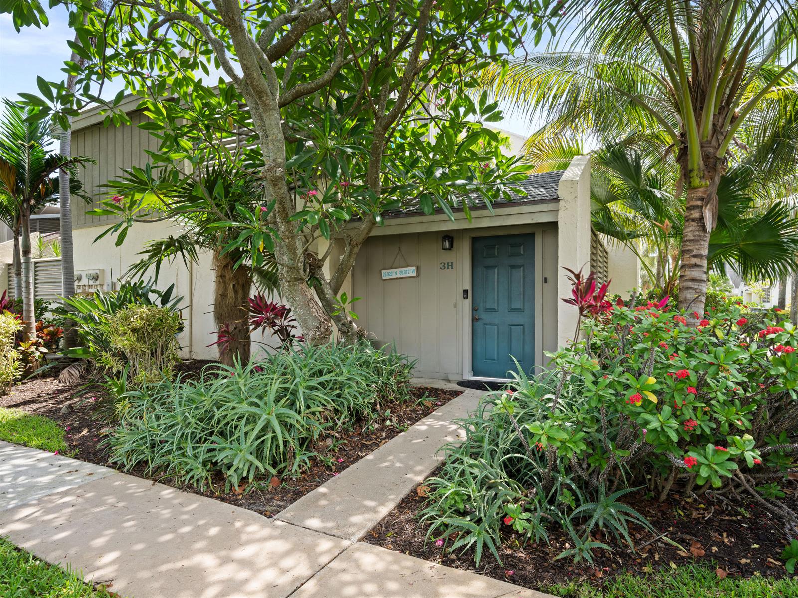 The exterior of a residential unit features a teal front door, landscaping, and palm trees — 1605 S Us Hwy 1 # 3h, Jupiter FL 33477, JUPITER, FL