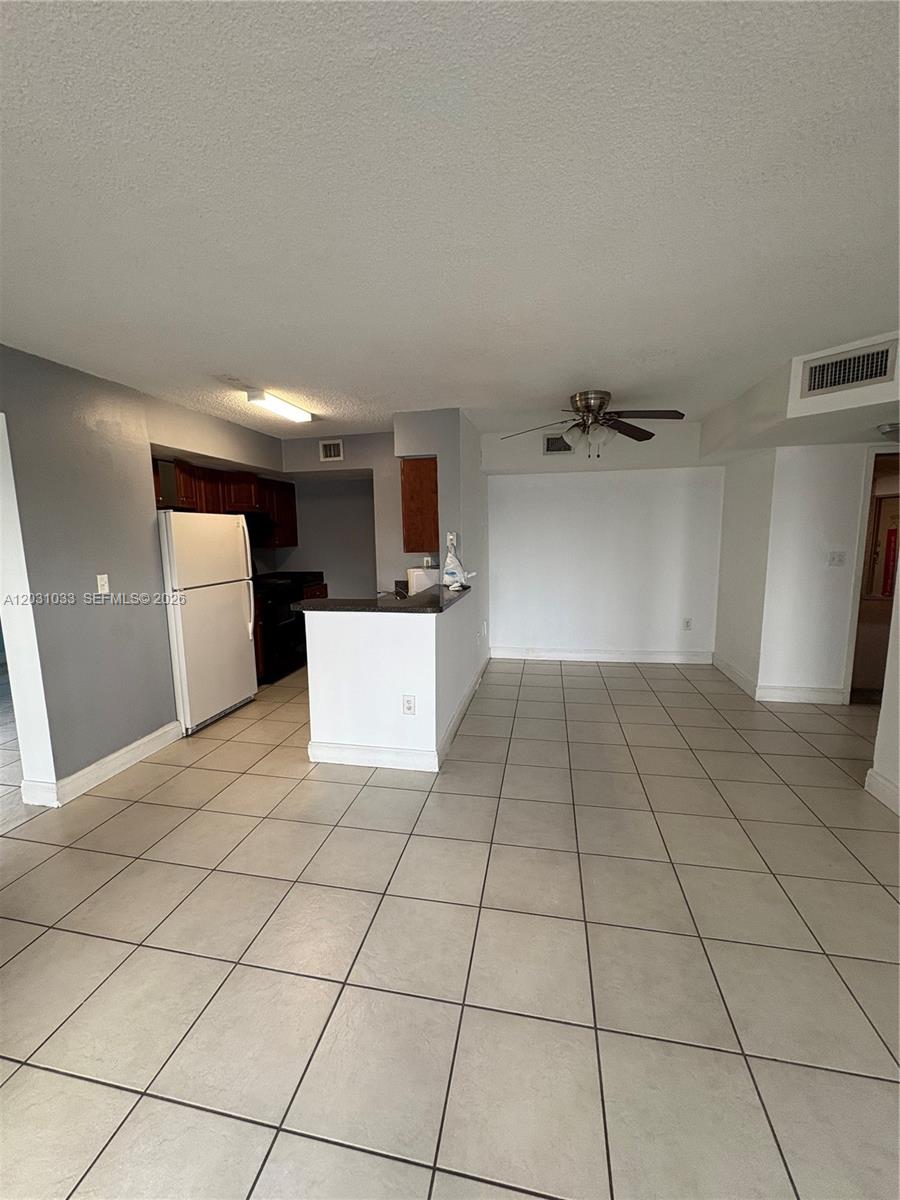 This room features a kitchen with white appliances, a breakfast bar, and tiled flooring — 15231 SW 80th St # 602, Miami FL 33193, MIAMI, FL