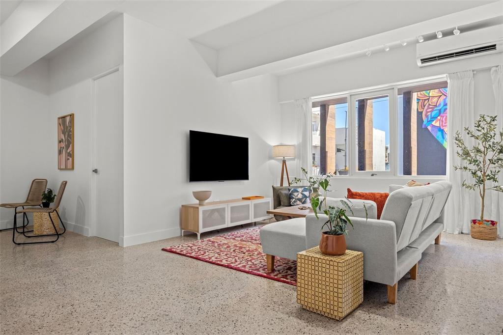 A bright living room features white walls, polished concrete floors, a sectional sofa, and windows — 606 CERRA ST, SAN JUAN, PR