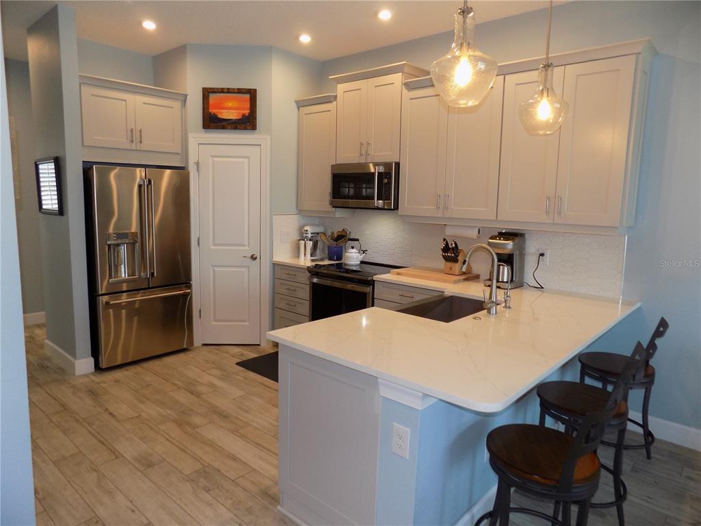 A kitchen with light gray cabinets, stainless steel appliances, and a white quartz countertop island — 2511 CORAL COURT, INDIAN ROCKS BEACH, FL