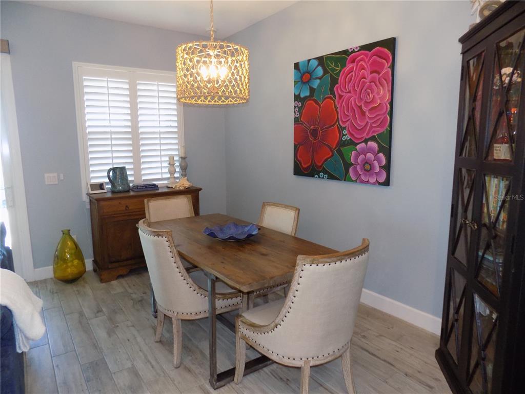 A dining room features a wooden table, upholstered chairs, a chandelier, and floral wall art — 2511 CORAL COURT, INDIAN ROCKS BEACH, FL