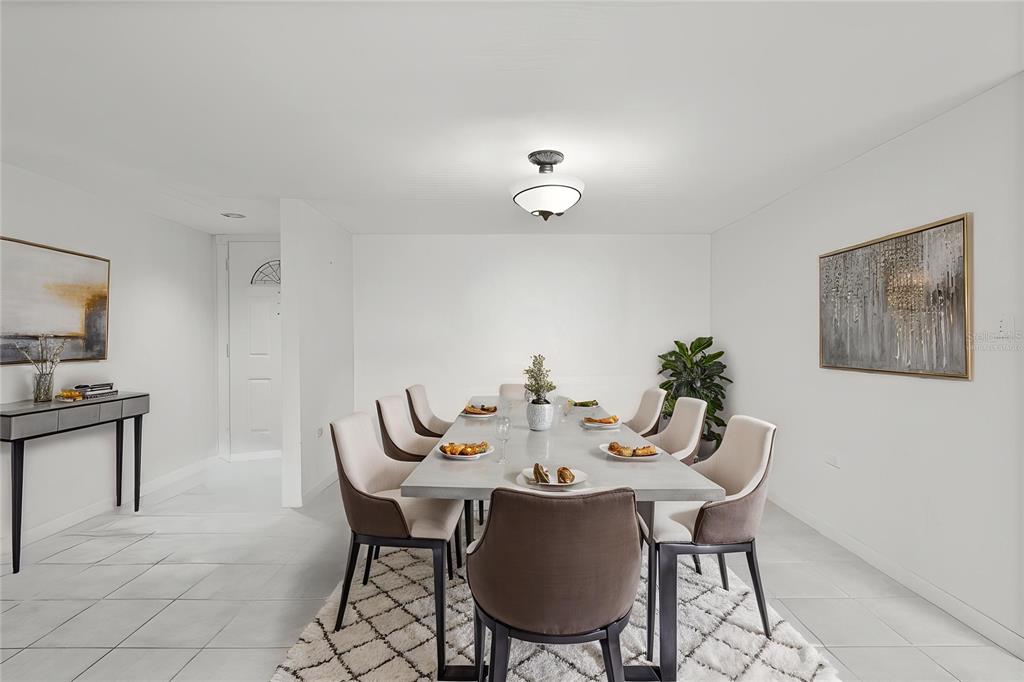 A dining room features a long gray table, eight upholstered chairs, and a white rug — 500 TREASURE ISLAND CAUSEWAY UNIT 406, TREASURE ISLAND, FL