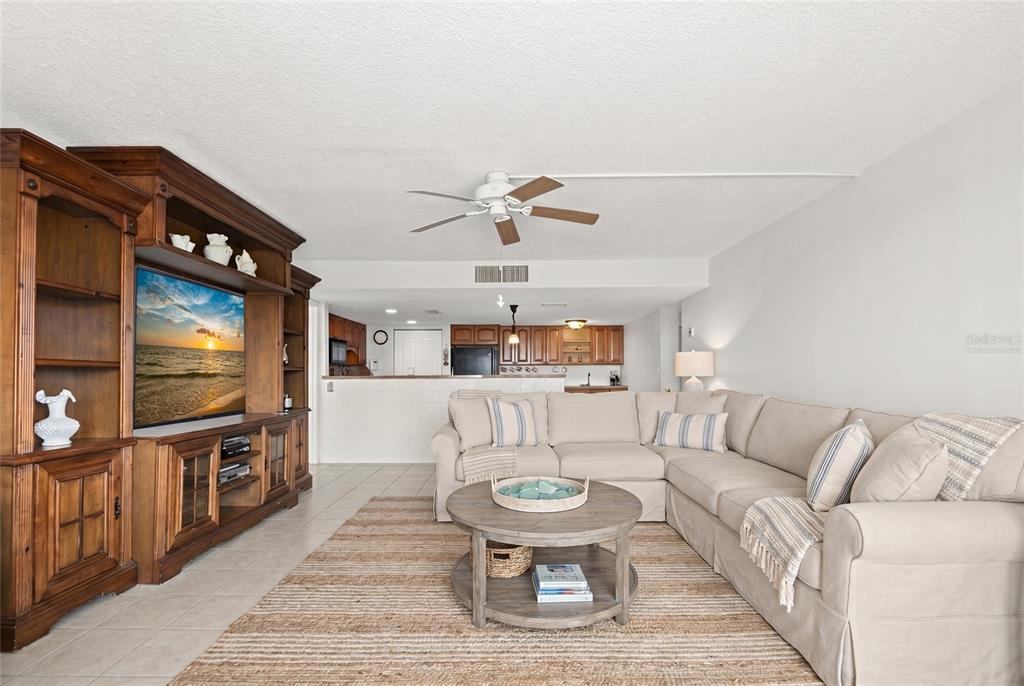 A living room features a large wooden entertainment center, a sectional sofa, and a rug — 500 TREASURE ISLAND CAUSEWAY UNIT 406, TREASURE ISLAND, FL