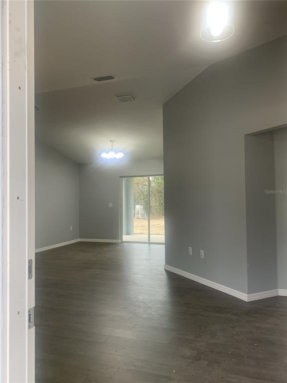 An interior view of a room with gray walls, dark wood-look flooring, and sliding glass doors — 16201 CRIDER ROAD, BROOKSVILLE, FL