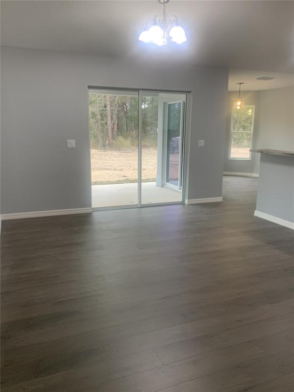 A dining area with gray walls, wood-look flooring, a chandelier, and sliding glass patio doors — 16201 CRIDER ROAD, BROOKSVILLE, FL