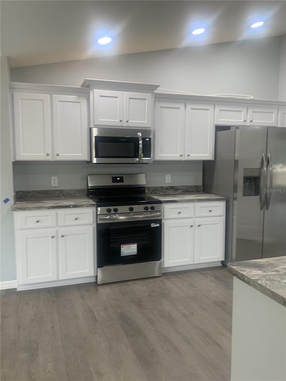 A kitchen features white cabinets, stainless steel appliances, and gray marble-patterned countertops — 16201 CRIDER ROAD, BROOKSVILLE, FL