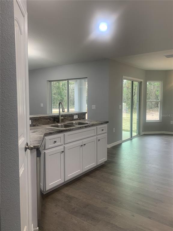 A kitchen with white cabinets and dark countertops overlooks an adjacent dining area with sliding doors — 16201 CRIDER ROAD, BROOKSVILLE, FL