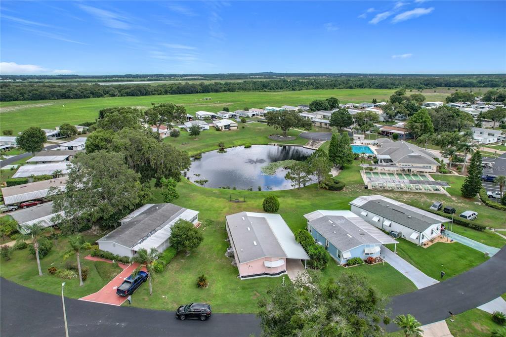 An aerial view shows a rectangular swimming pool surrounded by lounge chairs and a patio — 6044 GRAND OAKS DRIVE SE, WINTER HAVEN, FL