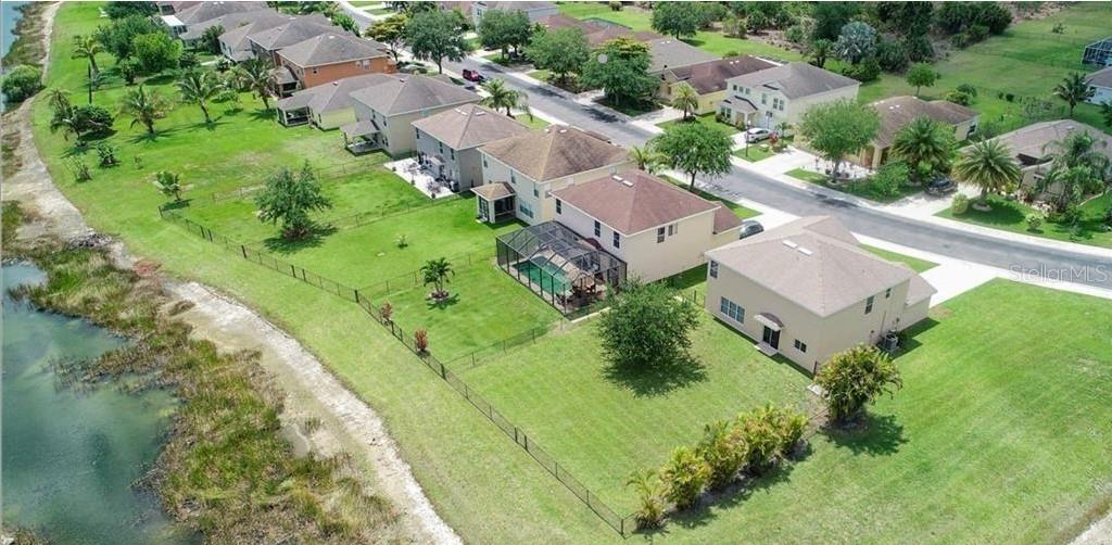 An aerial view shows a suburban neighborhood with houses, green lawns, and a nearby lake — 18168 HORIZON VIEW BOULEVARD, LEHIGH ACRES, FL