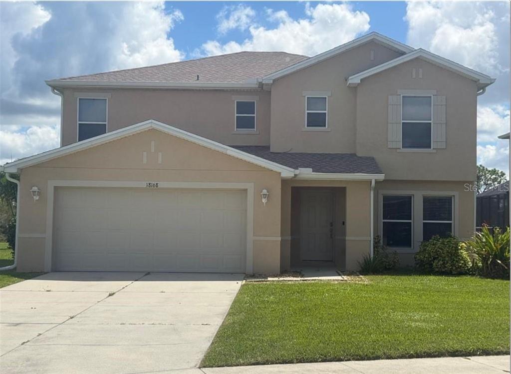 A two-story tan stucco house with a two-car garage and a front lawn — 18168 HORIZON VIEW BOULEVARD, LEHIGH ACRES, FL