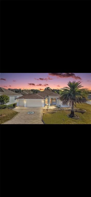 A single-story house with a two-car garage and a palm tree at sunset — 2725 HALSEY TERRACE, THE VILLAGES, FL