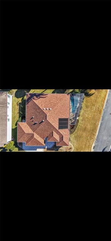 An aerial view shows a house with a shingled roof, solar panels, and a screened pool — 2725 HALSEY TERRACE, THE VILLAGES, FL