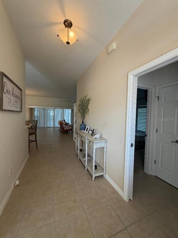 A tiled hallway features a console table, a ceiling light, and an open doorway — 2725 HALSEY TERRACE, THE VILLAGES, FL