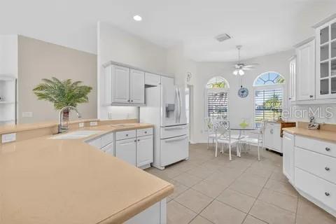 A bright kitchen features white cabinets, light countertops, and a dining area by a window — 2725 HALSEY TERRACE, THE VILLAGES, FL