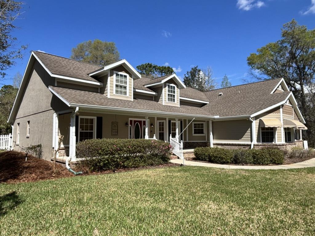 A two-story house with a brown shingled roof, dormer windows, and a front porch — 1815 SE 89TH LANE, OCALA, FL