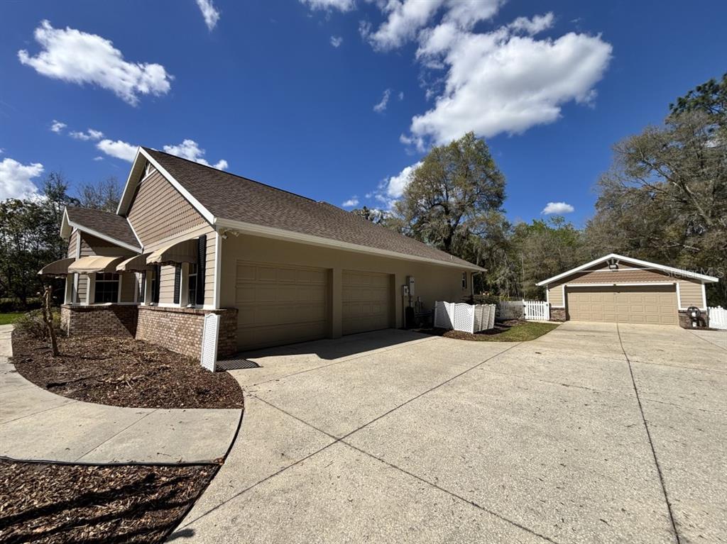A tan house with a two-car garage and a detached garage on a concrete driveway — 1815 SE 89TH LANE, OCALA, FL