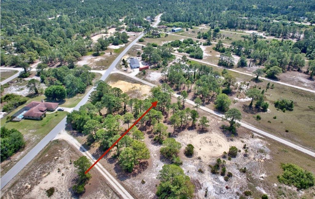 An aerial view shows a wooded lot with a dirt road and nearby houses — 328 TAHITI AVENUE, LAKE PLACID, FL