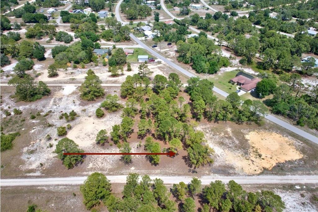 An aerial view shows a wooded, undeveloped residential lot bordered by a dirt road — 328 TAHITI AVENUE, LAKE PLACID, FL