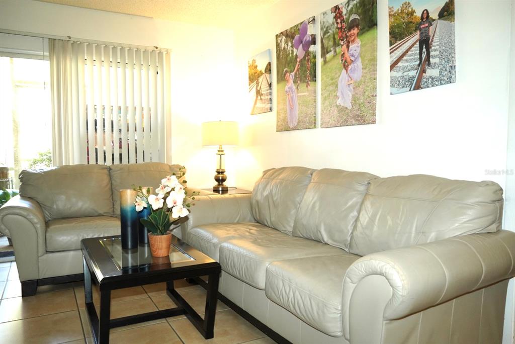 A living room features two light-colored leather sofas, a dark coffee table, and wall art — 1664 SUNNY BROOK LANE NE UNIT 103, PALM BAY, FL