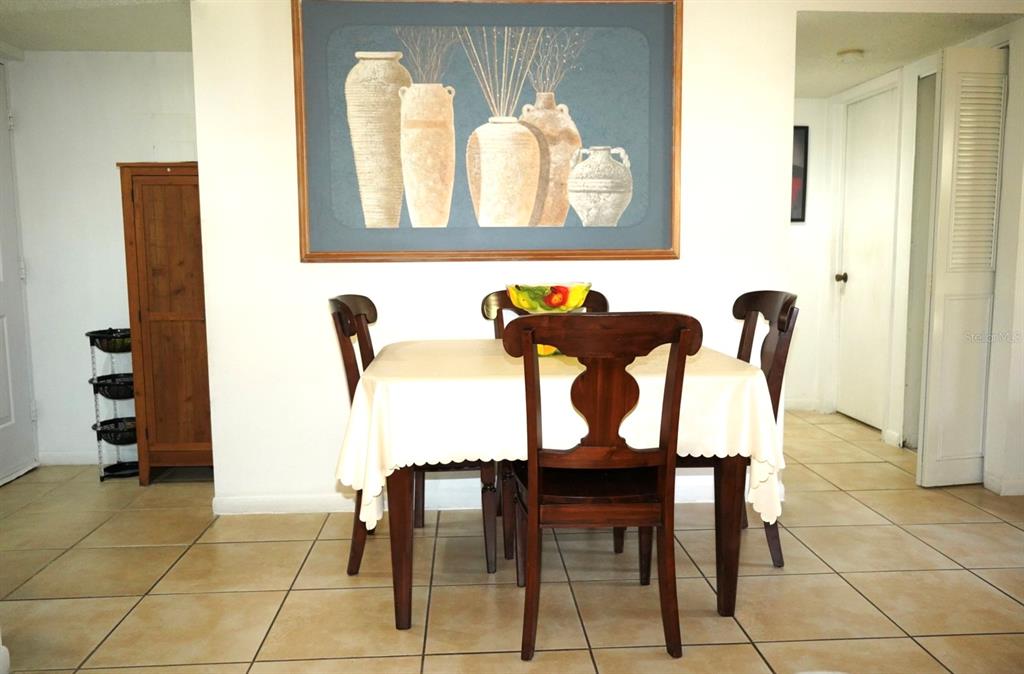 A dining area with a table, four chairs, tile flooring, and wall art — 1664 SUNNY BROOK LANE NE UNIT 103, PALM BAY, FL