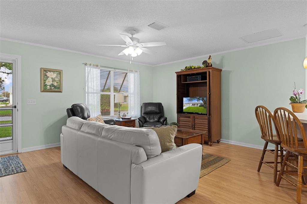 A living room features a white sofa, two black recliners, and a wooden entertainment center — 8015 SE 174TH BELHAVEN LOOP, THE VILLAGES, FL