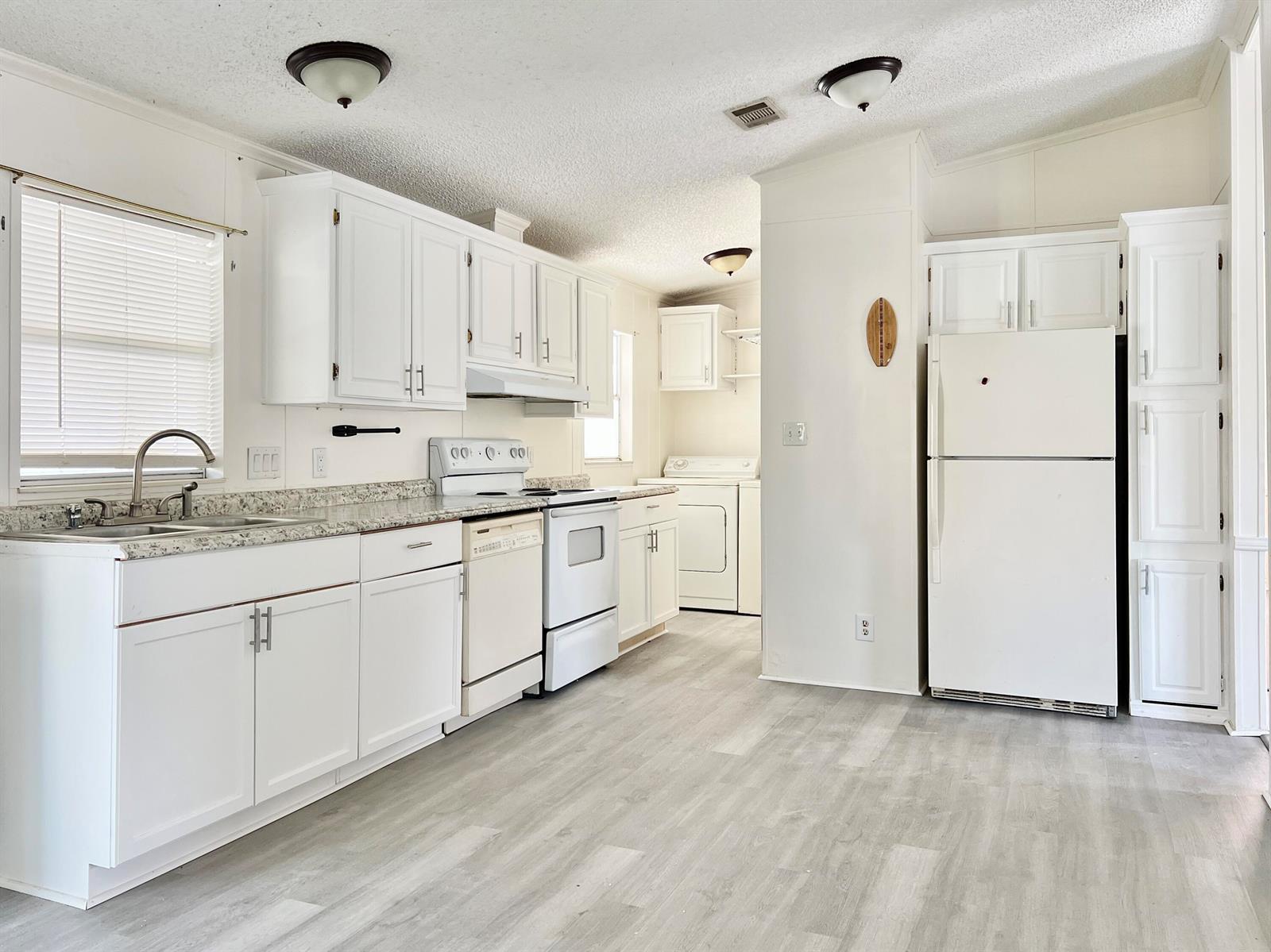 A kitchen with white cabinets, light countertops, white appliances, and light wood-look flooring — 183 Plantation Boulevard, Lake Worth FL 33467, LAKE WORTH, FL