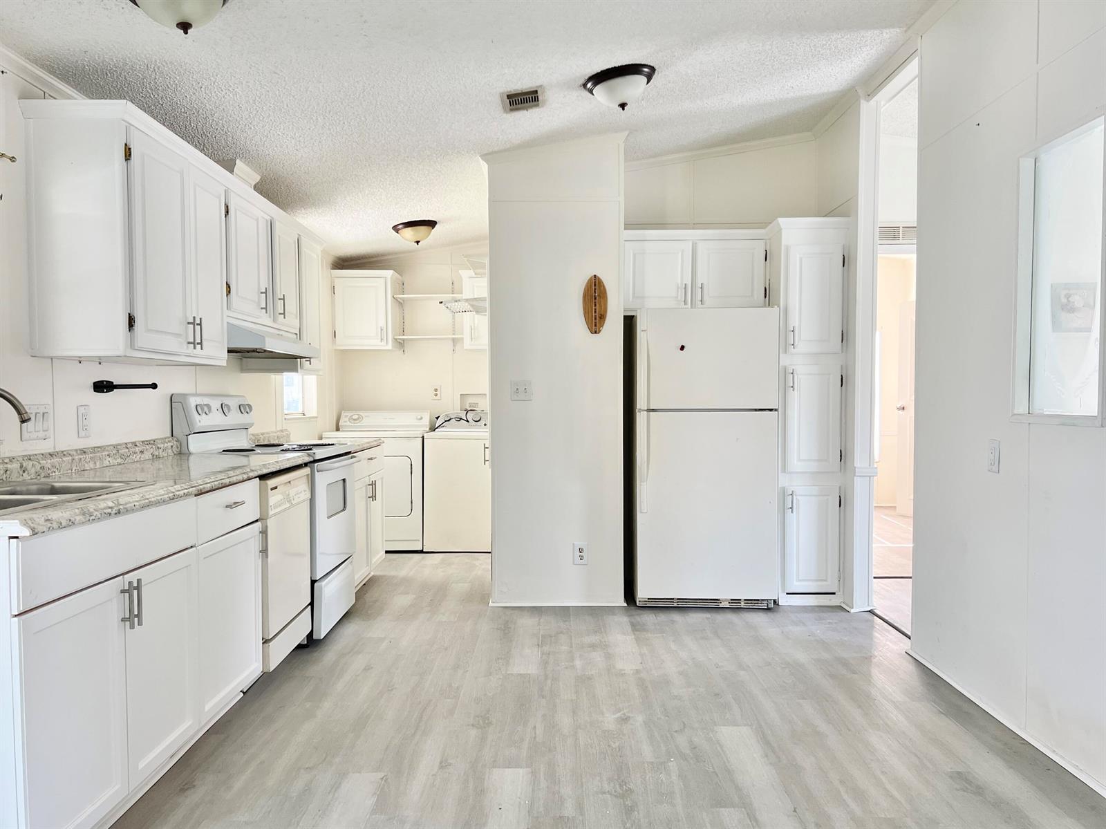 A white kitchen features light wood-look flooring, white cabinetry, and a white refrigerator — 183 Plantation Boulevard, Lake Worth FL 33467, LAKE WORTH, FL