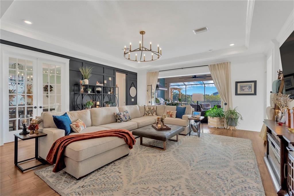 A living room features a large sectional sofa, a dark accent wall, and a chandelier — 7213 TALAMORE DRIVE, WESLEY CHAPEL, FL