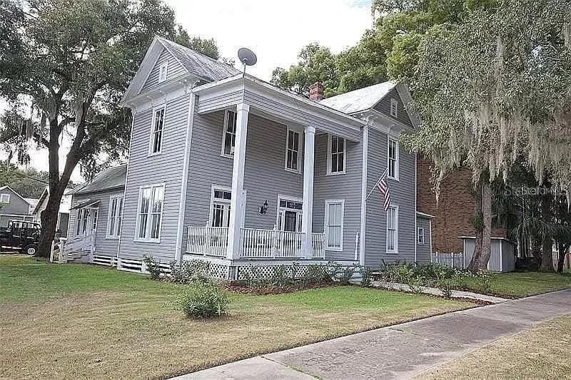A two-story gray house with a front porch and white trim stands on a lawn — 495 E PARKER STREET, BARTOW, FL
