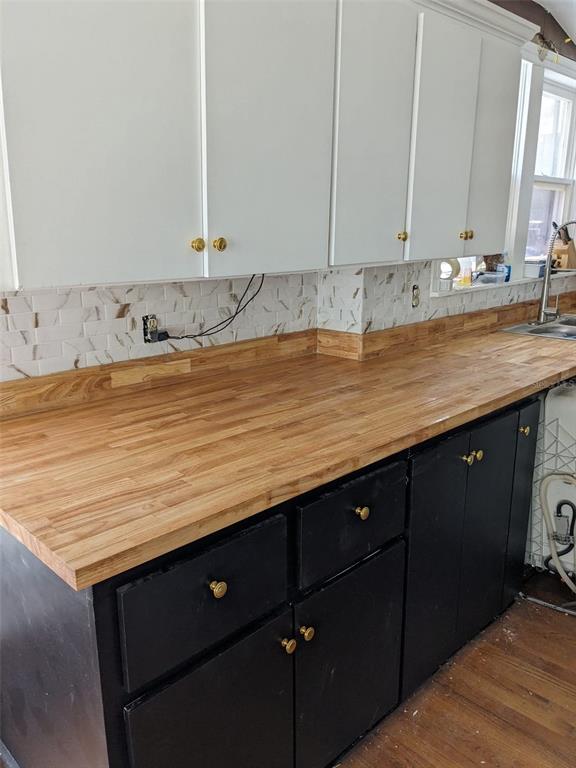 A kitchen features black lower cabinets, white upper cabinets, a gas stove, and wood countertops — 495 E PARKER STREET, BARTOW, FL
