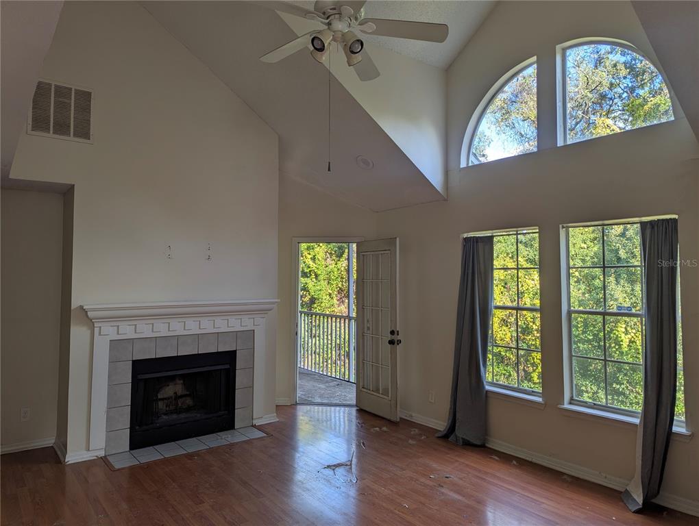 A living room with a fireplace, vaulted ceiling, ceiling fan, and large windows — 5956 WESTGATE DRIVE UNIT 203, ORLANDO, FL