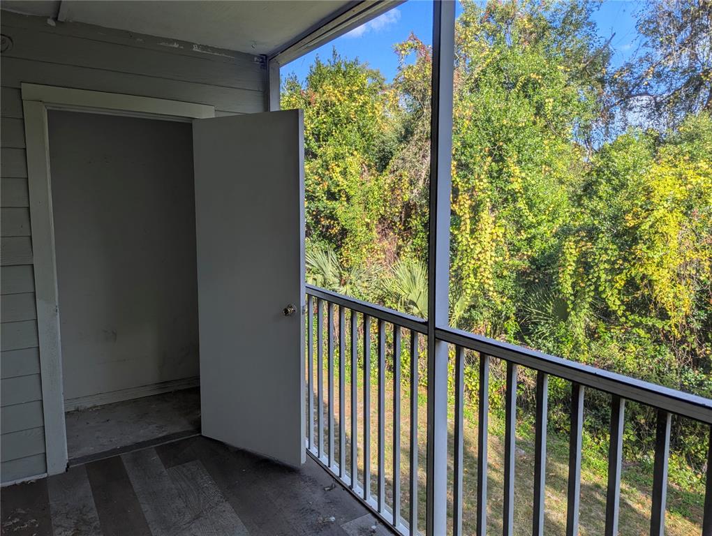 A screened-in balcony features a storage closet, gray wood-look flooring, and a metal railing — 5956 WESTGATE DRIVE UNIT 203, ORLANDO, FL