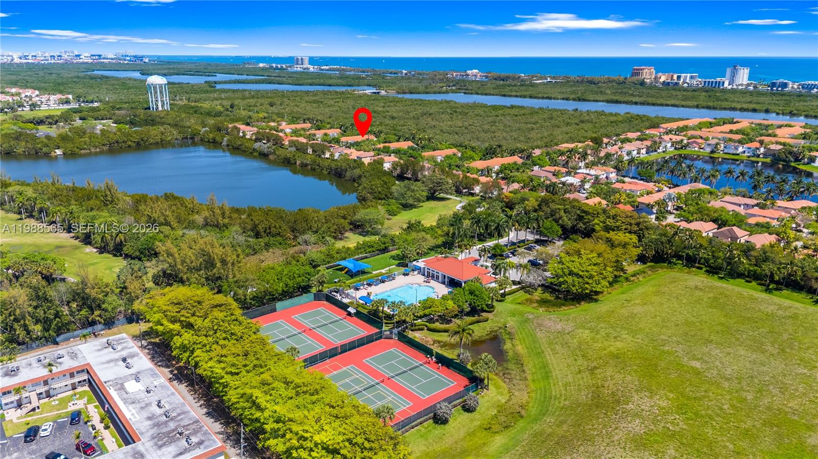 An aerial view shows a residential community with tennis courts, a swimming pool, and lakes — 1120 Canella Ln, Hollywood FL 33019, HOLLYWOOD, FL