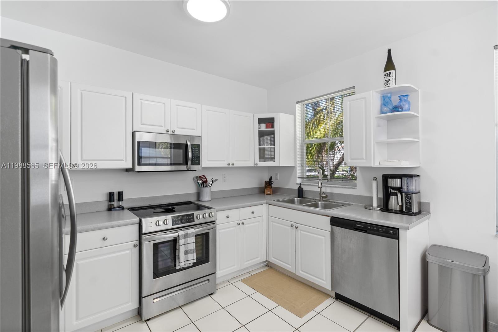A kitchen features white cabinets, stainless steel appliances, gray countertops, and white tile flooring — 1120 Canella Ln, Hollywood FL 33019, HOLLYWOOD, FL