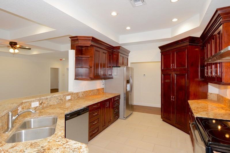 A kitchen with dark wood cabinets, granite countertops, stainless steel appliances, and tile flooring — 4935 Lame Panther Lane, Loxahatchee FL 33470, LOXAHATCHEE, FL