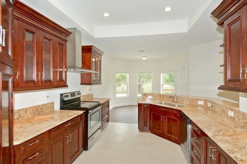 A kitchen with dark wood cabinets, granite countertops, stainless steel appliances, and tile flooring — 4935 Lame Panther Lane, Loxahatchee FL 33470, LOXAHATCHEE, FL