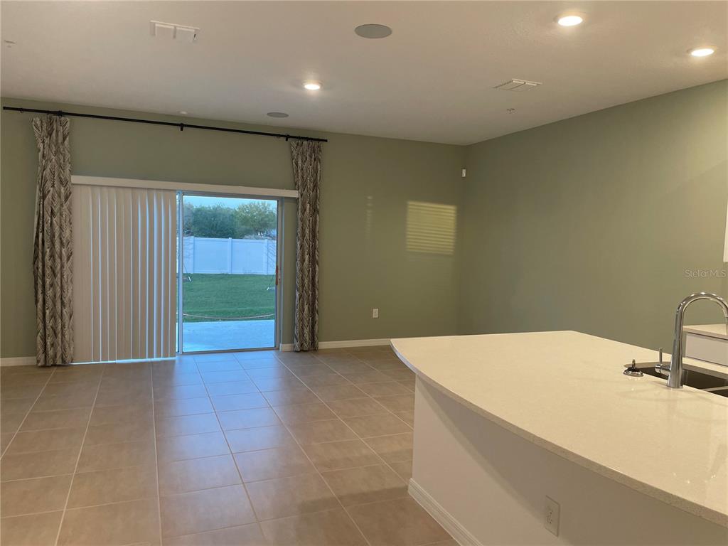 A kitchen island with a sink overlooks a living area with sliding glass patio doors — 4590 CALVARY WAY, ST CLOUD, FL