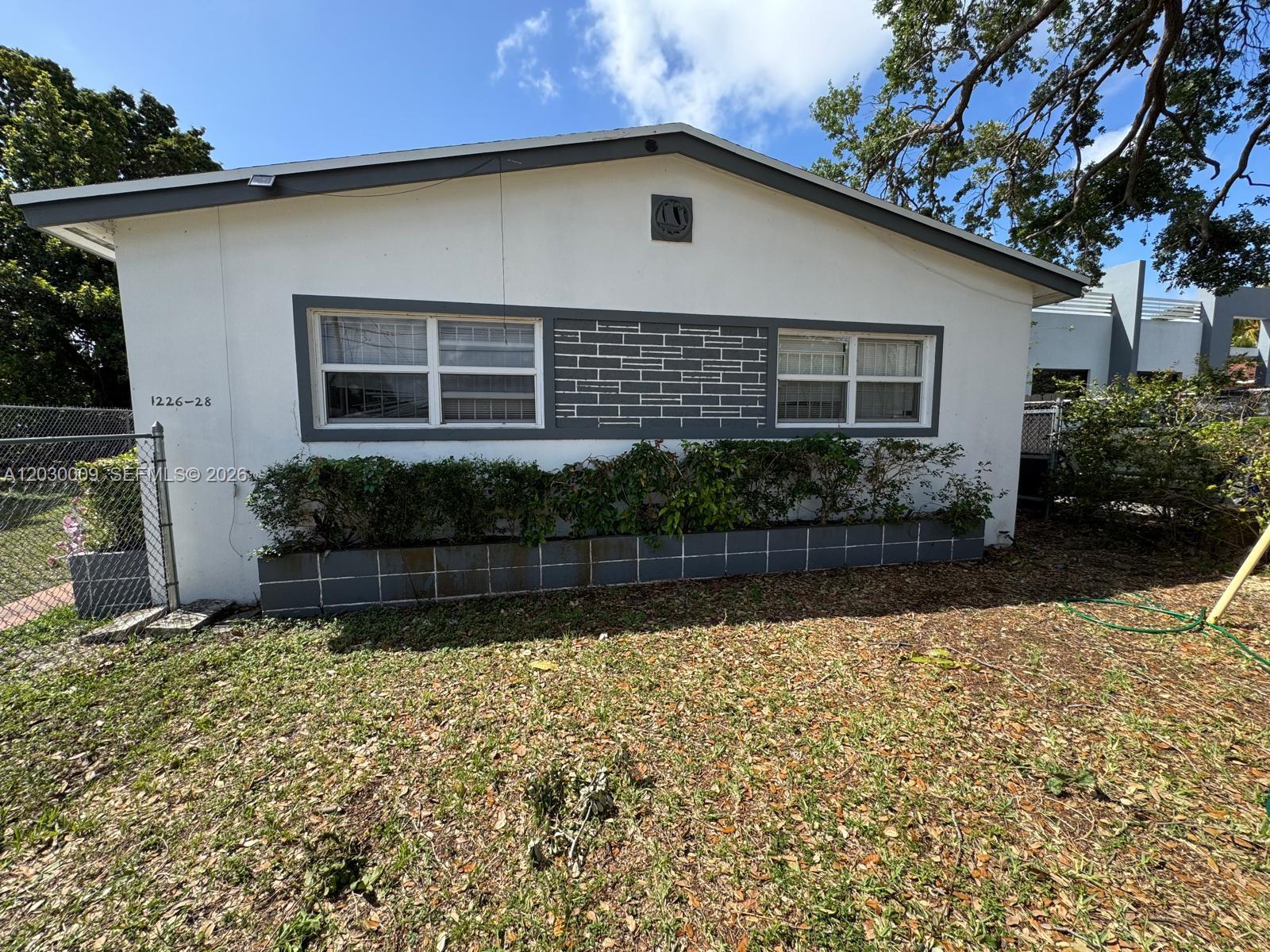 A single-story house exterior features white walls, gray trim, and a low concrete planter — 1226 NE 112th St # 1226, Miami FL 33161, MIAMI, FL